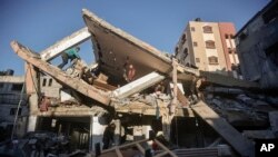 Palestinos inspeccionan los daños de una casa destruida tras los ataques aéreos israelíes en Khan Younis, en el sur de la Franja de Gaza, el domingo 7 de enero de 2024.