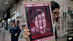 FILE - A protester holds a picture of Chinese human rights lawyer Wang Quanzhang during a protest outside the Chinese liaison office in Hong Kong, July 13, 2018.