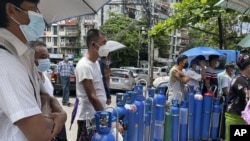 People queue with their oxygen tanks outside an oxygen refill station in Pazundaung township in Yangon, Myanmar, July 11, 2021.