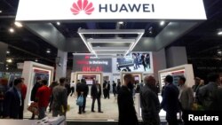 FILE - Attendees pass by a Huawei booth during the 2019 CES in Las Vegas, Jan. 9, 2019. 