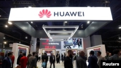 FILE - Attendees pass by a Huawei booth during the 2019 CES in Las Vegas, Nevada, U.S. Jan. 9, 2019. 