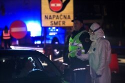 Medical staff checks a passenger in a car for the novel coronavirus at the border crossing with Italy in Vrtojba, Slovenia, March 11 , 2020.