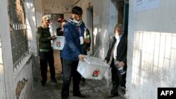 ঢাকায় বাংলাদেশের সাধারণ নির্বাচনের সময় একটি ভোট কেন্দ্রে ভোট শেষ হওয়ার পর নির্বাচন কর্মকর্তারা একটি সিল করা ব্যালট বাক্স বহন করছেন। ৭ জানুয়ারী, ২০২৪। 