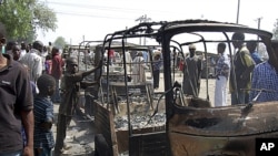 Residents survey vehicles damaged after a bomb blast at a primary school in Maiduguri, the capital of Nigeria's Borno state, February 29, 2012.