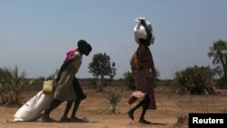 FILE - Women carry food at a food distribution site in Nyal, Unity State, Sudan.
