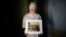 FILE - Maryam Kamalmaz holds a photo of her father, Majd Kamalmaz, with some of his 14 grandchildren in Grand Prairie, Texas, Jan. 17, 2024. The Syrian-born American psychotherapist died while being held in Syria. His family has filed a lawsuit against the Syrian government.