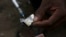 A syringe sucks up a mixture of heroin and water prepared on a foil wrap as addicts shoot up in Stone Town, Zanzibar, Dec. 2009 file photo.