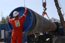 FILE - A worker puts a cap to a pipe at the construction site of the Nord Stream 2 gas pipeline, near the town of Kingisepp, Leningrad region, Russia, June 5, 2019.