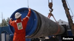 FILE - A worker puts a cap to a pipe at the construction site of the Nord Stream 2 gas pipeline, near the town of Kingisepp, Leningrad region, Russia, June 5, 2019. 