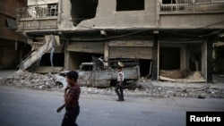 Children walk near damaged buildings in rebel-held Ain Tarma, eastern Damascus suburb of Ghouta, Syria, September 17, 2016.