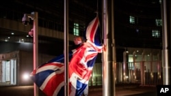 A worker raises the Union Flag prior a meeting between European Commission President Ursula von der Leyen and British Prime Minister Boris Johnson at EU headquarters, Dec. 9, 2020.