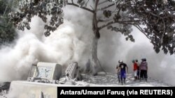Warga berada di jalan yang diselimuti abu vulkanik dari letusan Gunung Semeru di Lumajang, Jawa Timur, 2 Desember 2020. (Foto: Antara/Umarul Faruq via REUTERS)
