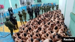 En esta foto publicada en las redes sociales por las Fuerzas Armadas de Ecuador y distribuida por Reuters se observa a policías y soldados armados custodiando a reclusos en la prisión de Cuenca, el 14 de enero de 2024.