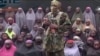  This undated image taken from video distributed Sunday, Aug. 14, 2016, shows an alleged Boko Haram soldier standing in front of a group of girls alleged to be some of the 276 abducted Chibok schoolgirls held since April 2014, in an unknown location.