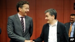 Dutch Finance Minister and chairman of the eurogroup Jeroen Dijsselbloem, left, shakes hands with Greek Finance Minister Euclid Tsakalotos during a meeting of eurozone finance ministers at the EU Council building in Brussels, Aug. 14, 2015.