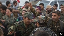 Members of the U.S.-backed Syrian Democratic Forces (SDF) dance a traditional Syrian 'Dabka" as they celebrate in front of stadium that was the site of Islamic State fighters' last stand in the city of Raqqa, Syria, Oct. 20, 2017. 