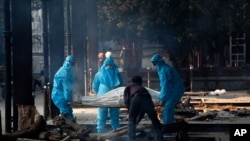 Health workers in personal protective equipment carry the body of a COVID-19 victim for cremation in New Delhi, India, Nov. 19, 2020.