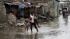 A man carries his children after Cyclone Idai at Praia Nova, in Beira, Mozambique, March 23, 2019. 