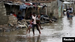A man carries his children after Cyclone Idai at Praia Nova, in Beira, Mozambique, March 23, 2019. 