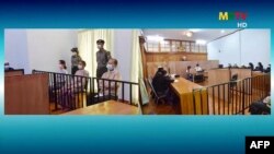 This screengrab provided via AFPTV and taken from a broadcast by Myanmar Radio and Television (MRTV) in Myanmar, May 24, 2021 shows detained civilian leader Aung San Suu Kyi (2nd L) during her first court appearance in Naypyidaw.