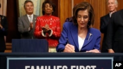 FILE - House Speaker Nancy Pelosi of California, accompanied by other legislators, signs the Coronavirus Aid, Relief and Economic Security Act, on Capitol Hill, March 27, 2020, in Washington. 