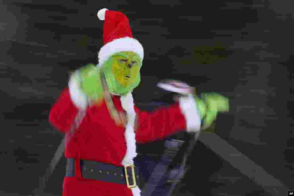 A skier dressed as the Grinch wearing a Santa Claus outfit skis for charity at the Sunday River Ski Resort, Dec. 11, 2022, in Newry, Maine.