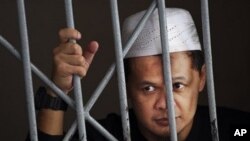 Suspected militant Abdullah Sunata stands behind bars inside a holding cell at a district court in Jakarta, Indonesia (File Photo - March 30, 2011)
