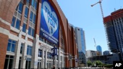 FILE - A cyclist passes past the American Airlines Center, home of the Dallas Mavericks and the Dallas Stars, in Dallas, Texas, April 16, 2020. 