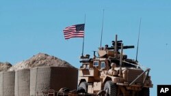 FILE - In this April 4, 2018 file photo, a U.S. soldier sits on an armored vehicle at a newly installed position, near the tense front line between the U.S-backed Syrian Manbij Military Council and the Turkish-backed fighters, in Manbij, north Syria. 