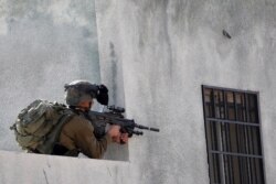 An Israeli soldier points his weapon during a Palestinian protest against Jewish settlements, in Kafr Qaddum in the Israeli-occupied West Bank, Nov. 13, 2020.