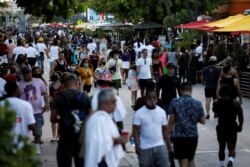 FILE - People walk along Ocean Drive during spring break festivities, amid the coronavirus outbreak, in Miami Beach, Florida, March 5, 2021.