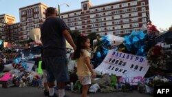 FILE - People gather at a makeshift memorial outside Dallas police headquarters, July 12, 2016. Five Dallas officers were shot and killed by a sniper during a Black Lives Matter march.
