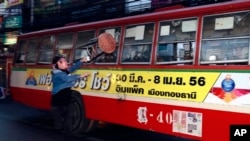 Seorang demonstran anti-pemerintah menyerang bus berisi orang-orang yang diduga mendukung pemerintah di Bangkok, Sabtu (30/11). (AP/Wason Wanichakom)
