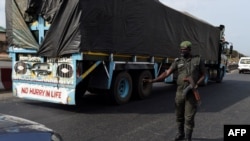 A police officer, wearing a face mask customised for the anti-robbery Rapid Respond Squad (RRS) as preventive measure against the COVID-19 coronavirus, flags down a car at a check point in Lagos, on April 20, 2020. 