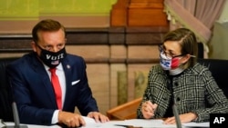 Iowa Secretary of State Paul Pate, left, and Iowa Gov. Kim Reynolds tally the votes cast by members of Iowa's Electoral College, Dec. 14, 2020, at the Statehouse in Des Moines, Iowa.
