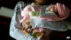 En esta foto de archivo del 14 de mayo de 2015, una niña de 13 años sostiene a su bebé de un mes en un albergue para niños con problemas en Ciudad del Este, Paraguay.