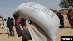 A worker of World Food Programme (WFP) carries a bag of relief grains to be distributed to Sudanese refugees who have fled the violence in their country, near the border between Sudan and Chad, in Koufroun, Chad April 28, 2023.