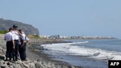 Police officers inspect metallic debris found on a beach in Saint-Denis on the French Reunion Island in the Indian Ocean on August 2, 2015, close to where a Boeing 777 wing part believed to belong to missing flight MH370 washed up last week.