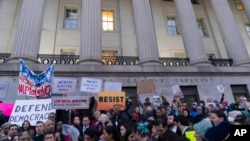 People listen to speakers during a rally against Elon Musk outside the U.S. Treasury Department in Washington, Feb. 4, 2025. 