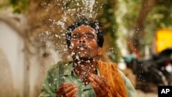 FILE - A worker splashes water to cool himself off on a hot summer afternoon in Prayagraj, Uttar Pradesh, India, June 13, 2019. Temperatures reached 48 degrees in some areas.