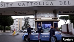 Police officers stand next to a car outside the Gemelli hospital where Pope Francis has gone to continue treatment for ongoing bronchitis in Rome, Feb. 14, 2025.
