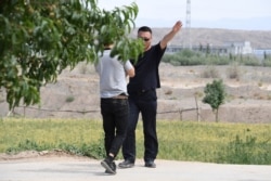 FILE - An AFP video journalist, left, is escorted away while filming at what is believed to be a reeducation camp where mostly Muslim ethnic minorities are detained, in China's northwestern Xinjiang region, June 2, 2019.