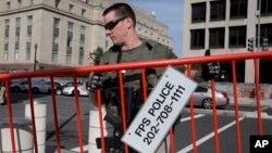 An armed U.S. Marshal lifts the security barricade around the federal courthouse where Libyan militant Ahmed Abu Khattala's hearing was held, in Washington, Oct. 20, 2014.