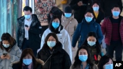 Commuters wearing face masks to protect against the spread of the coronavirus walk through a subway station in Beijing, March 3, 2021. 