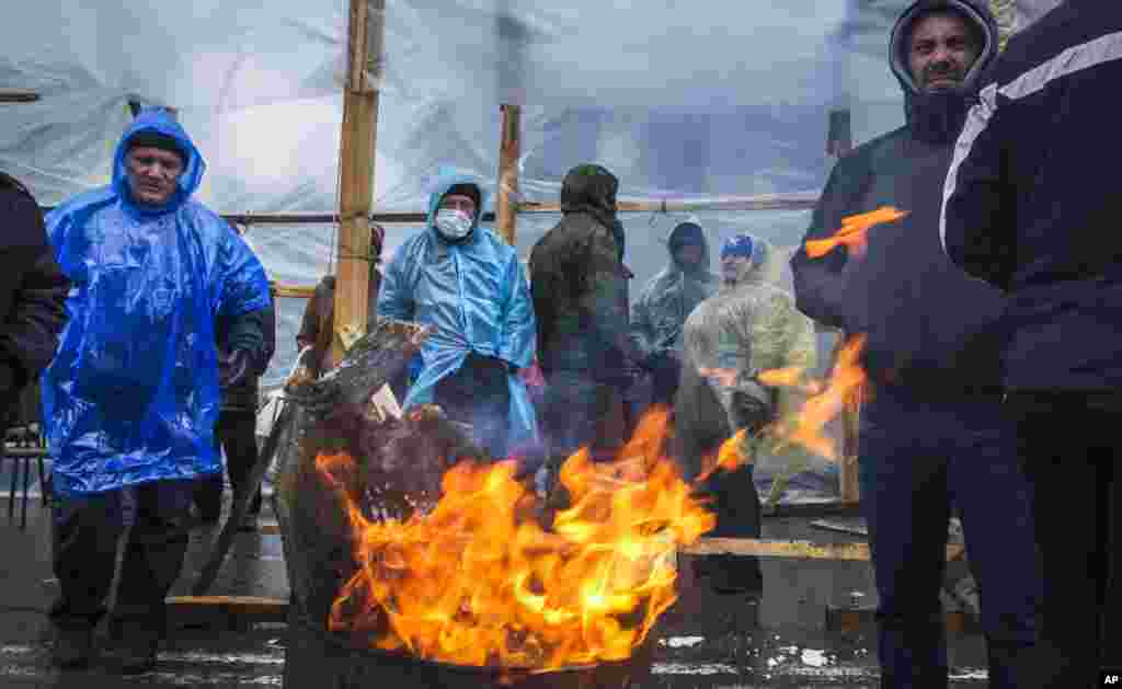 A group of pro-Russian activists warm themselves at a bonfire next to barricades in front of an entrance to the Ukrainian regional office of the Security Service in Luhansk, Ukraine, April 11, 2014.