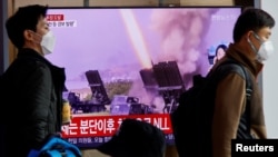 Men walk past a TV broadcasting a news report on North Korea firing a ballistic missile off its east coast, in Seoul, South Korea, Nov. 3, 2022. 