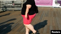 FILE - A woman walks along a boardwalk in New York.