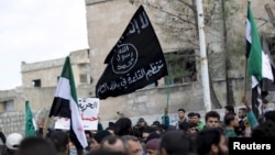 FILE - Protesters carry Al-Qaida flags during an anti-government demonstration after Friday prayers in the town of Marat Numan in Idlib province, Syria, on March 11, 2016.