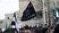 FILE - Protesters carry Al-Qaida flags during an anti-government demonstration after Friday prayers in the town of Marat Numan in Idlib province, Syria, on March 11, 2016.