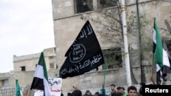 ফাইল- ইদলিব প্রদেশের মারাত নুমান শহরে জুম্মার নামাজের পর সরকার বিরোধী বিক্ষোভে প্রতিবাদকারীরা আল কায়েদার পতাকা বহন করছে। সিরিয়া, মার্চ ১১,২০১৬। 